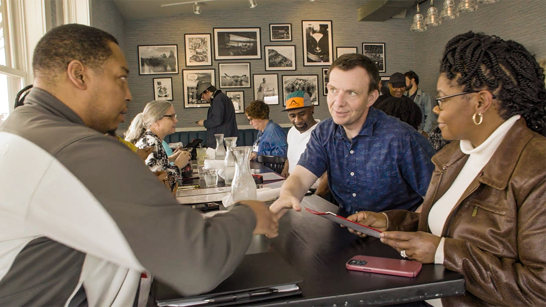 Three people greeting each other in a restaurant